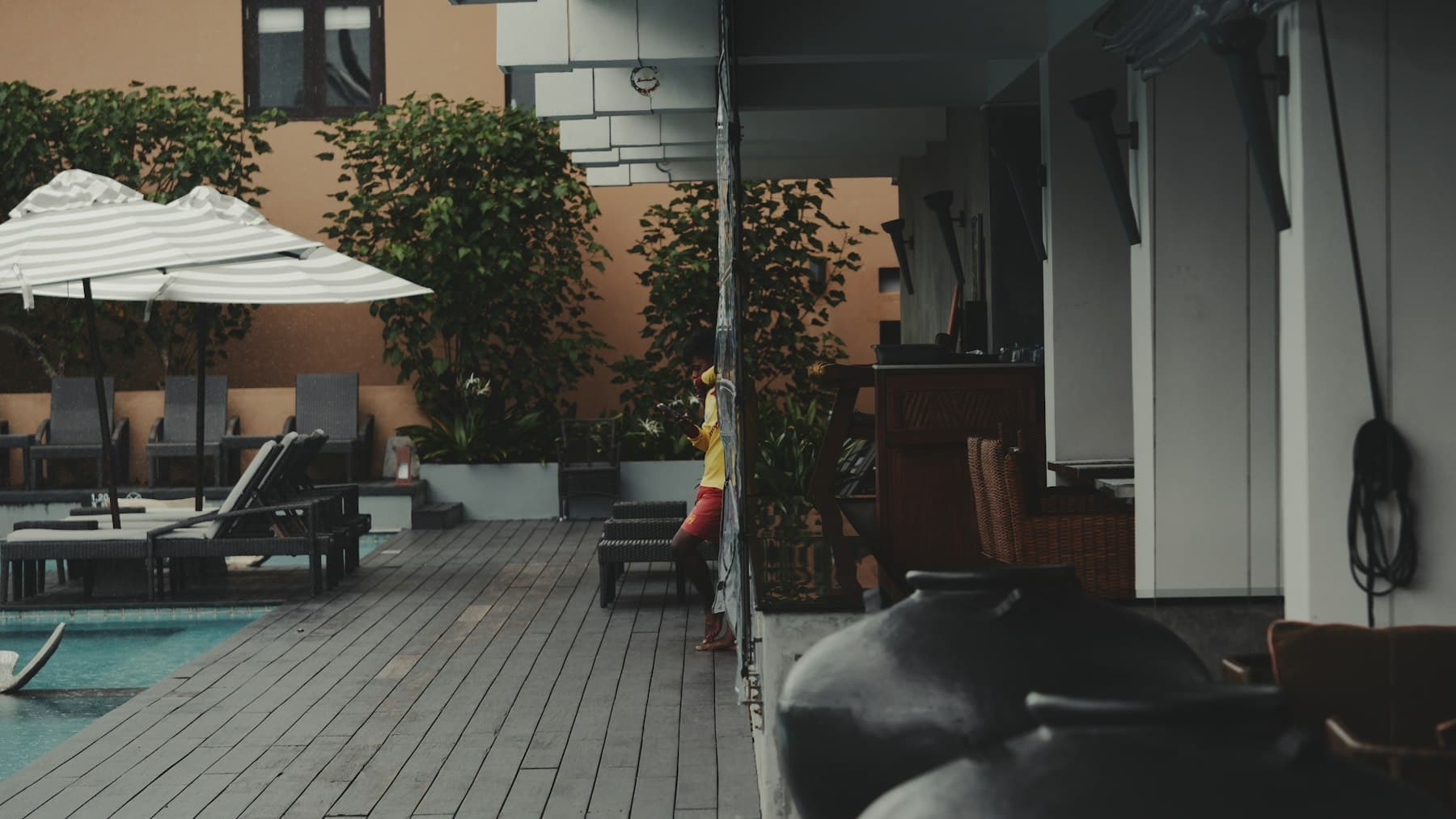 Resort-style pool terrace with lounge chairs, umbrellas, and planters