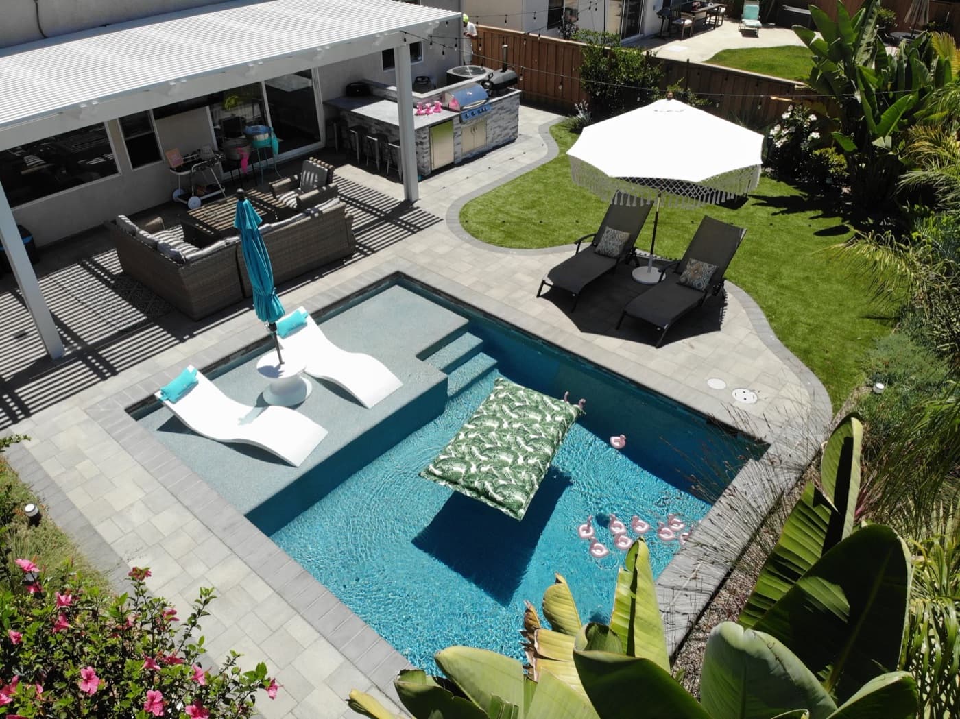 Resort pool with in-water loungers and an outdoor kitchen in Chula Vista by Modern Yardz