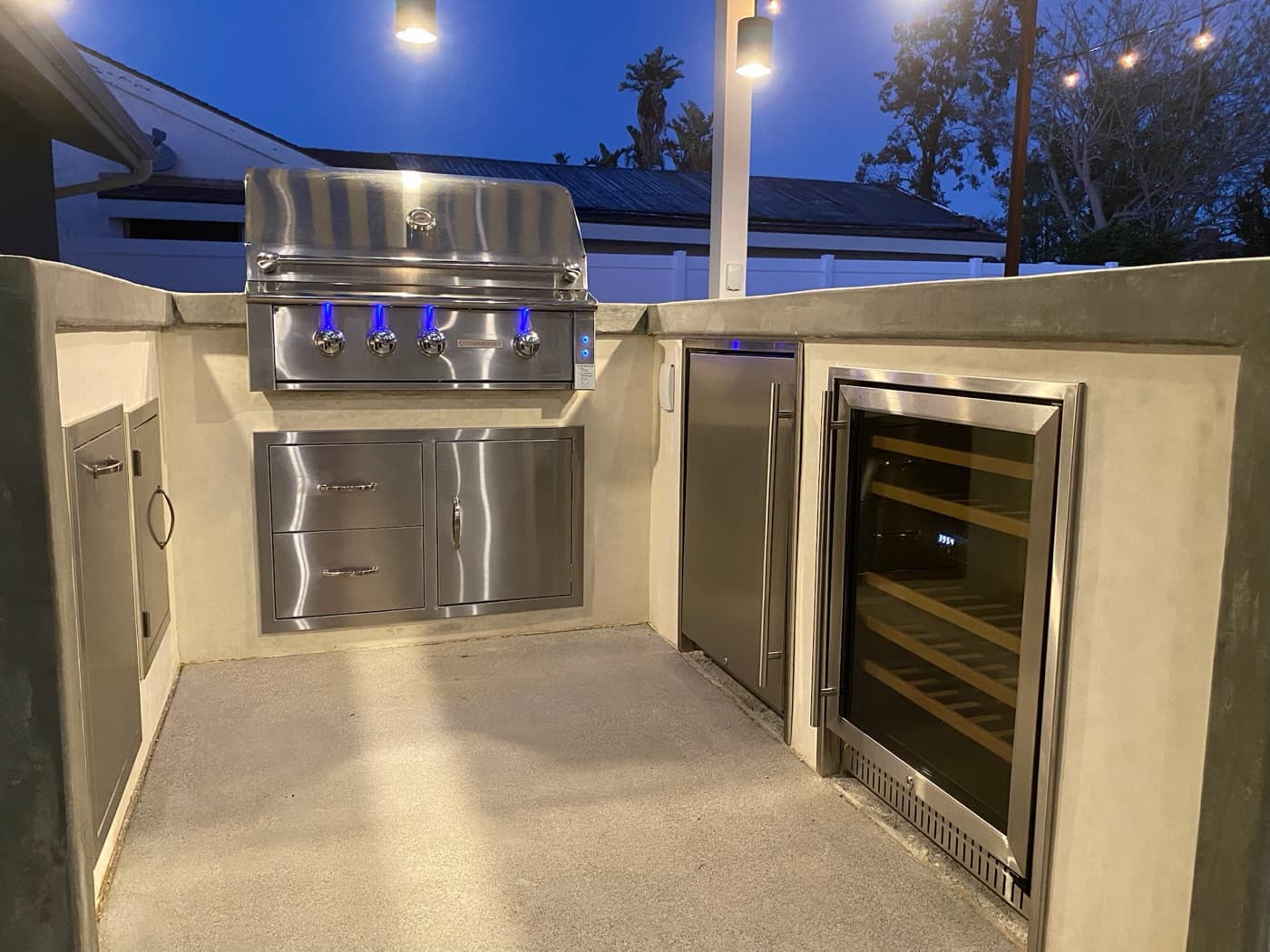 Sleek outdoor kitchen with grill and wine fridge at dusk in Chula Vista by Modern Yardz