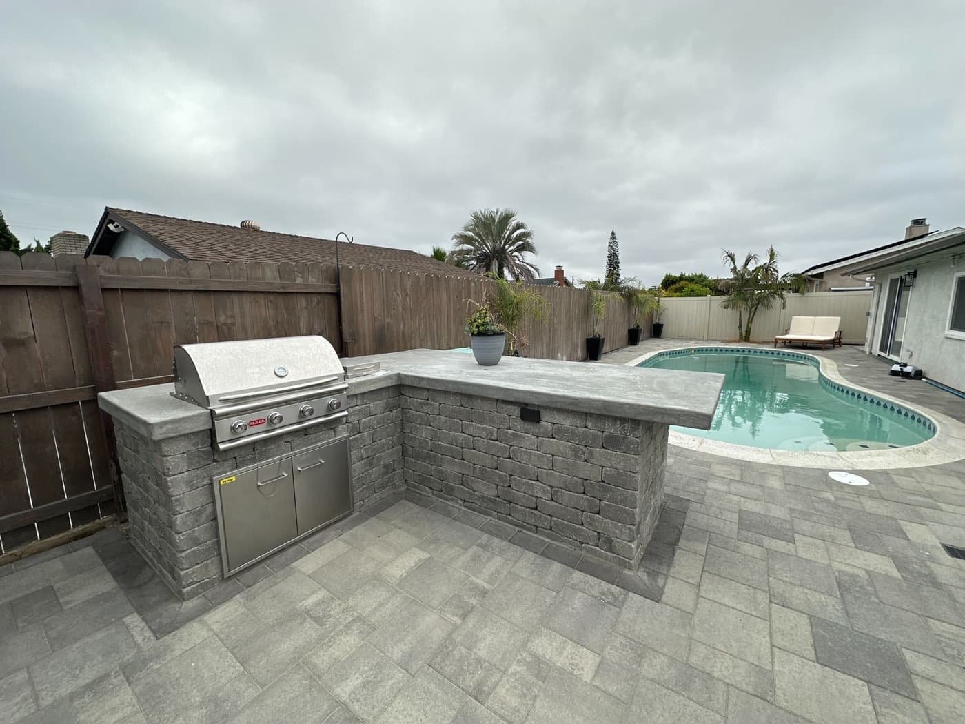 Outdoor kitchen and pool with a paver patio in Chula Vista by Modern Yardz