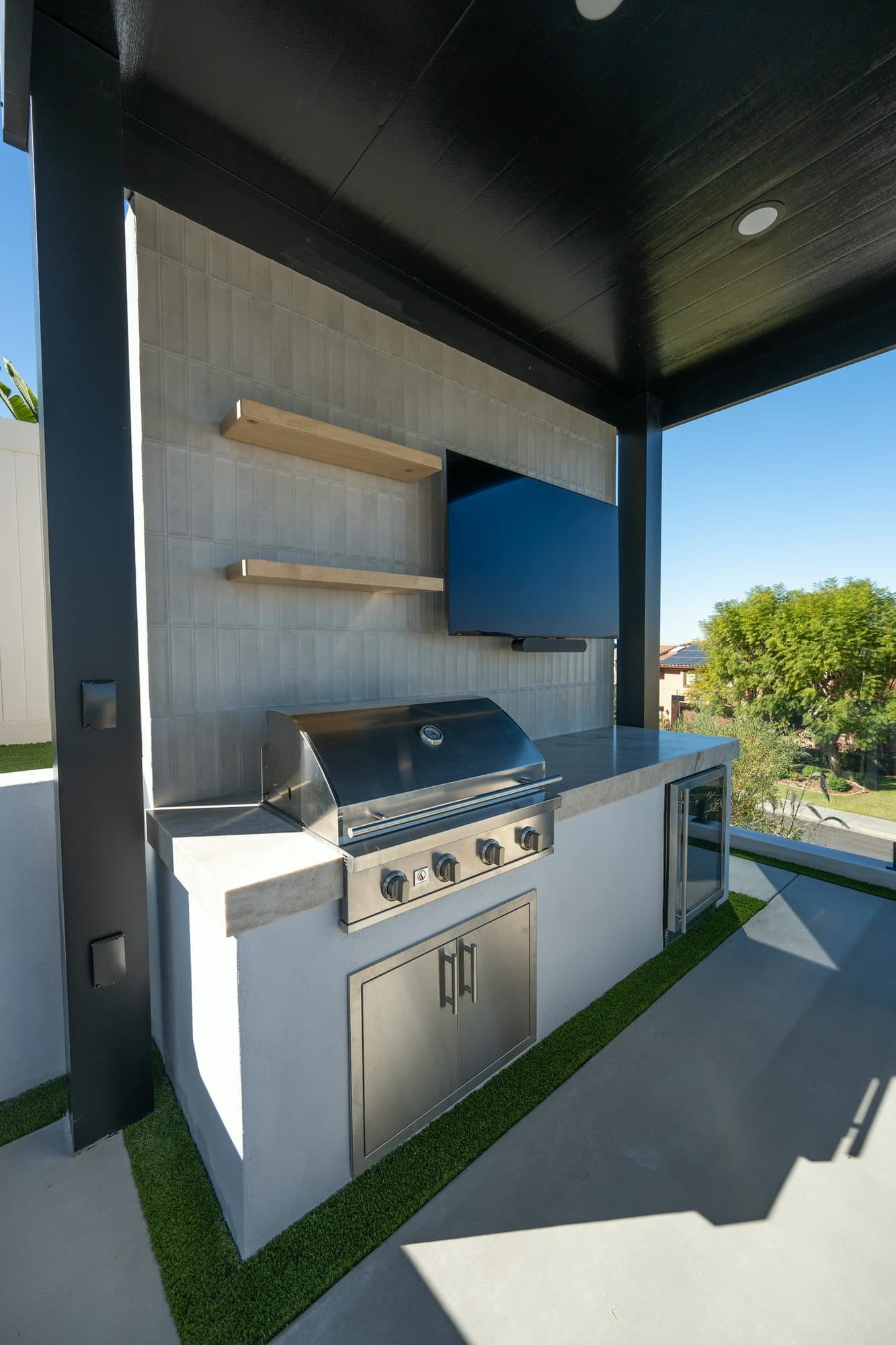 Outdoor kitchen with floating shelves, grill and storage drawers