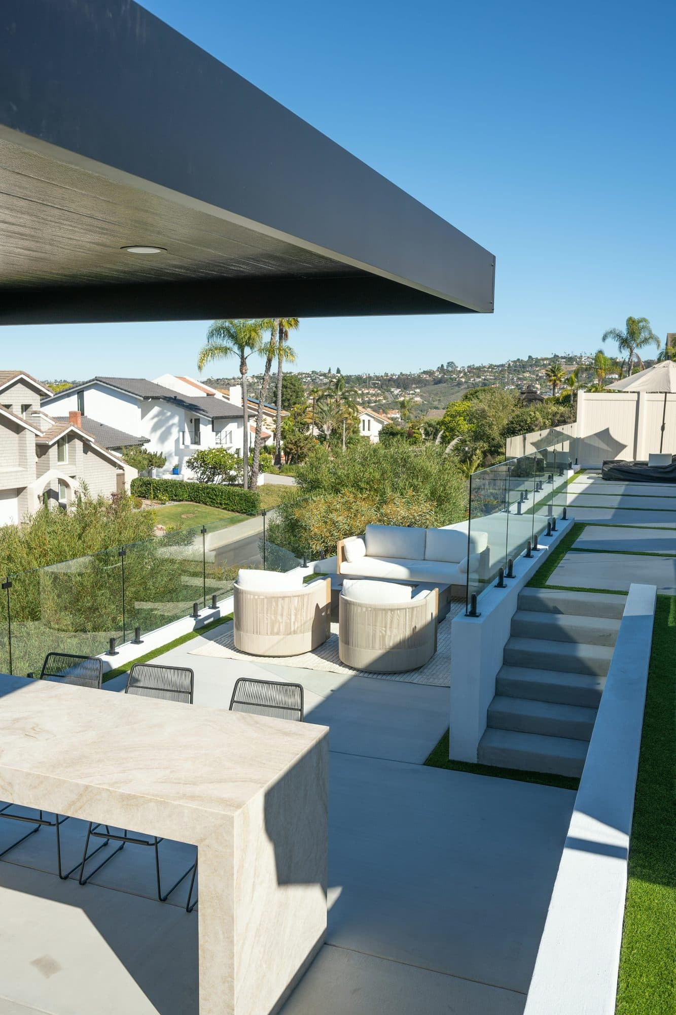 Multi-level ocean-view backyard in Carlsbad with poured concrete pads, steps, and turf inlays by Modern Yardz