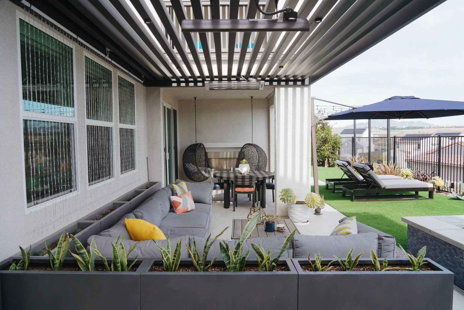 Louvered pergola over a patio lounge attached to the house by Modern Yardz in Chula Vista