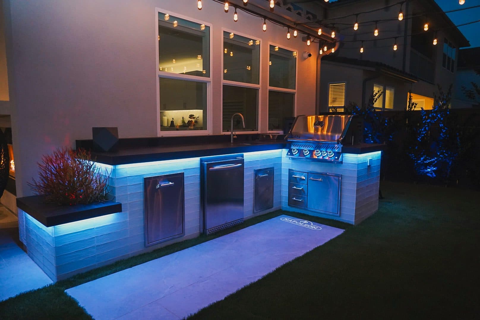 Outdoor kitchen at dusk with color-changing LED lighting under the counter