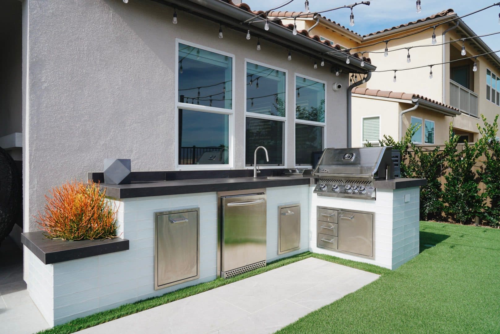 Outdoor kitchen with a built-in grill and white glass-tile island