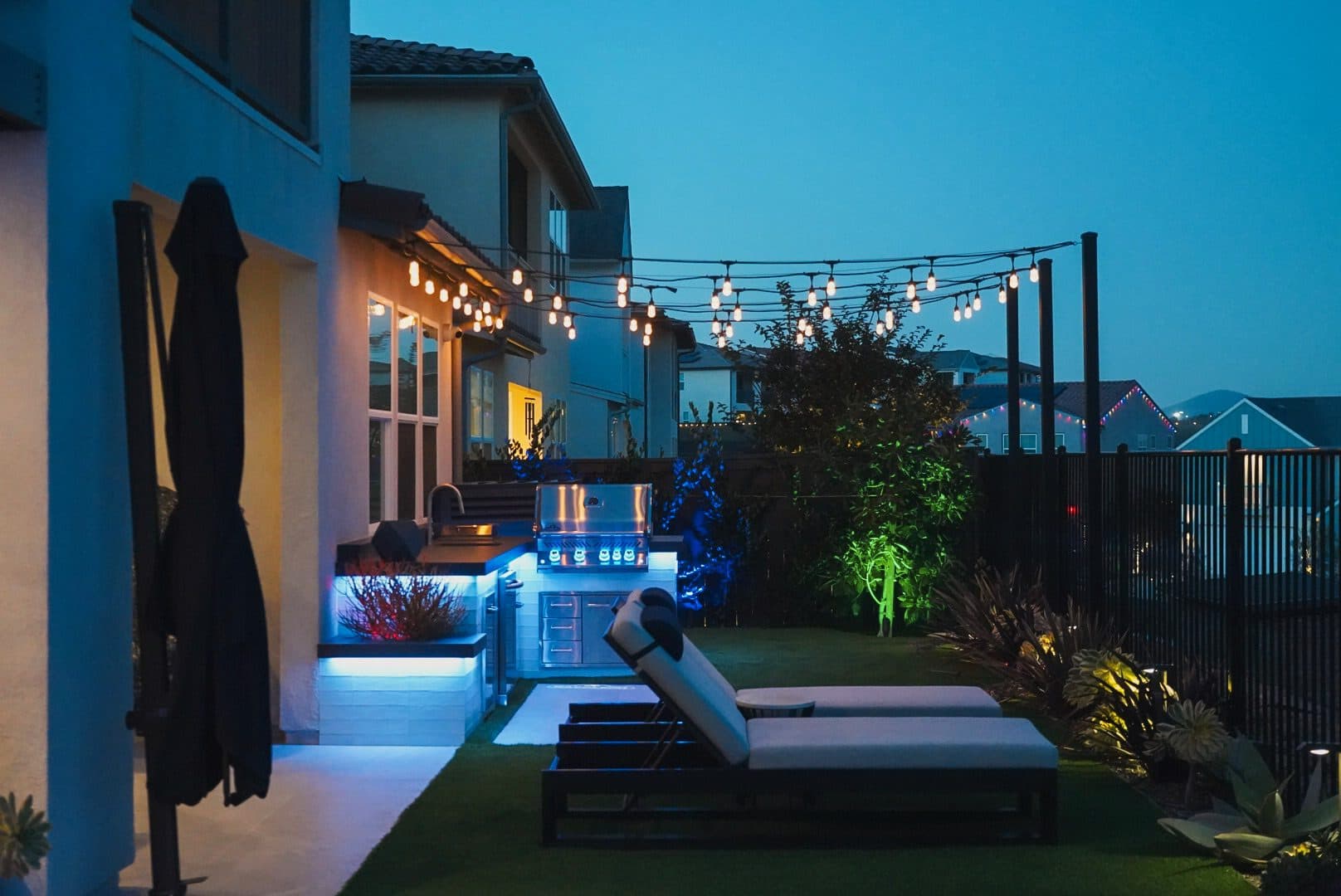 Concealed color-changing LED lighting washing the stucco walls at dusk, with string lights above the spool