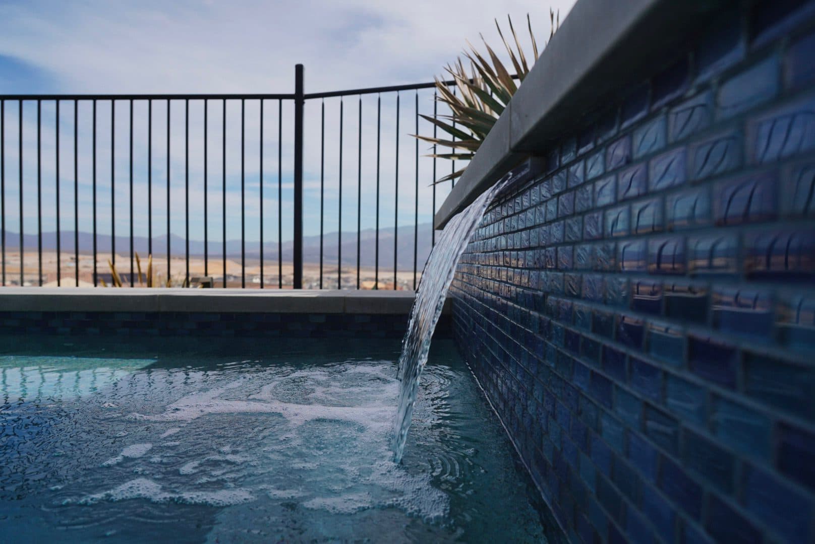 Sheer-descent water spillway pouring into the glass-tile spool