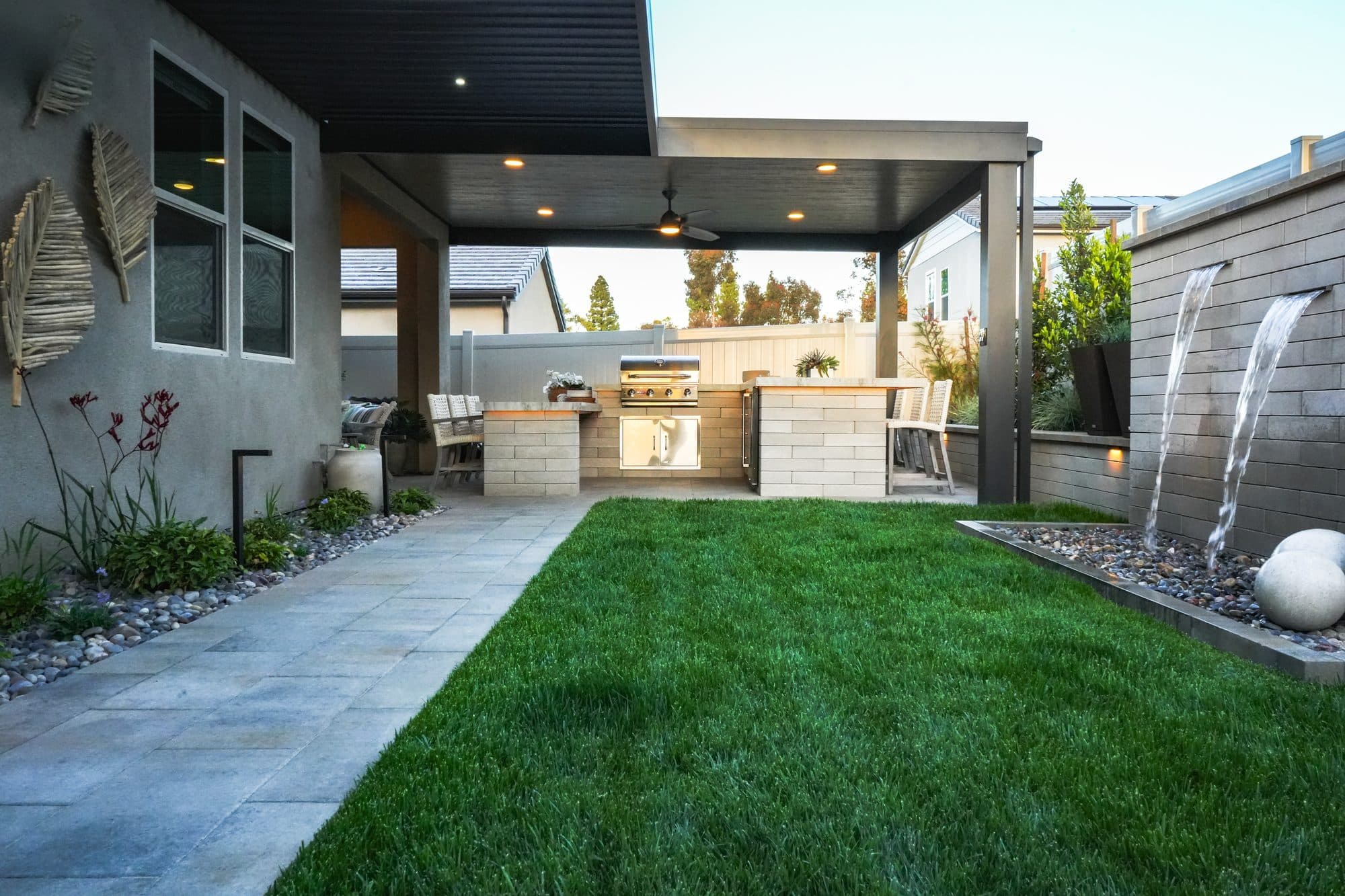 Wide view of the backyard with the kitchen, lawn and water feature