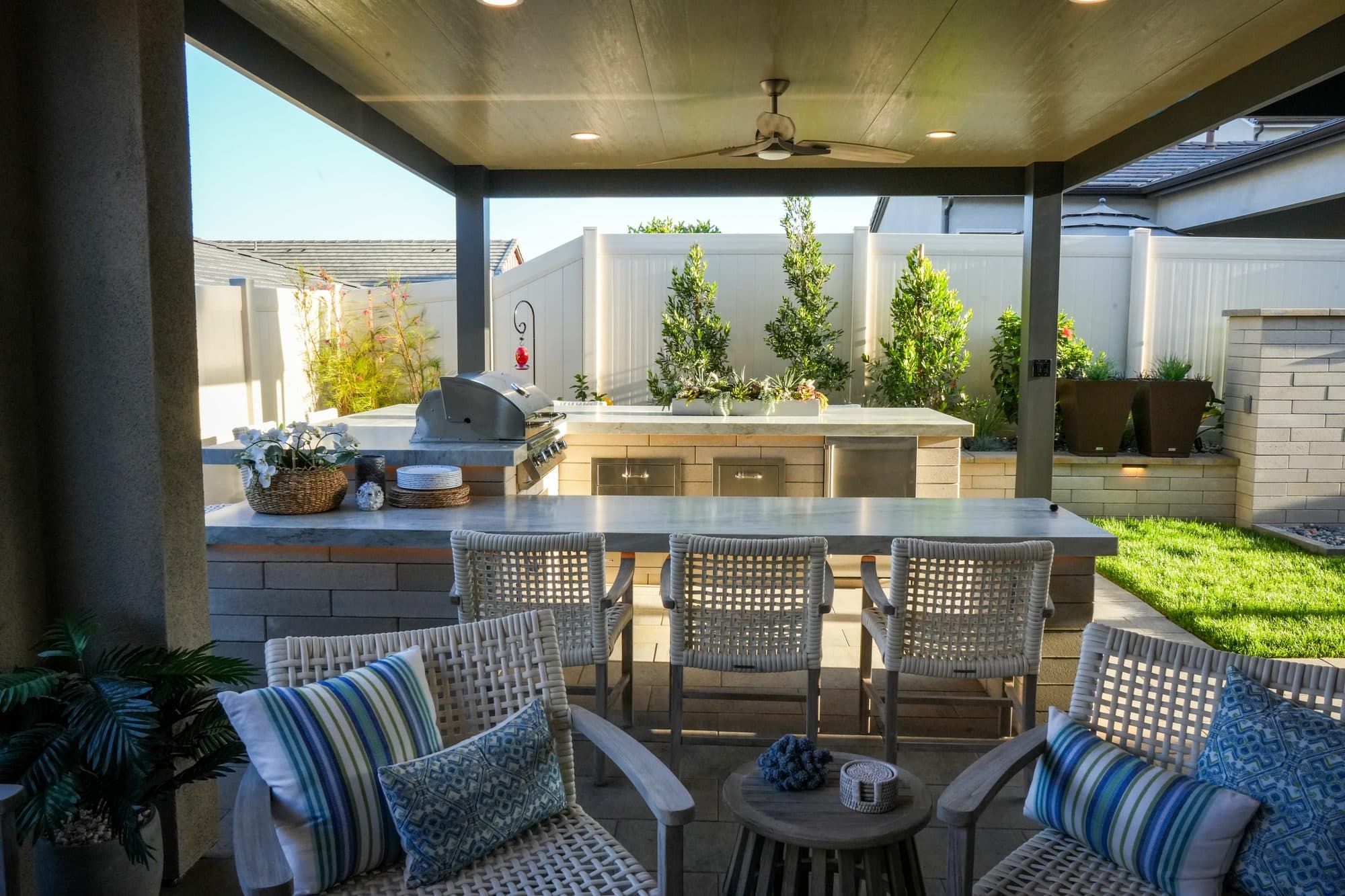 Covered patio with dining, ceiling fans, and an outdoor kitchen by Modern Yardz in Rancho Bernardo