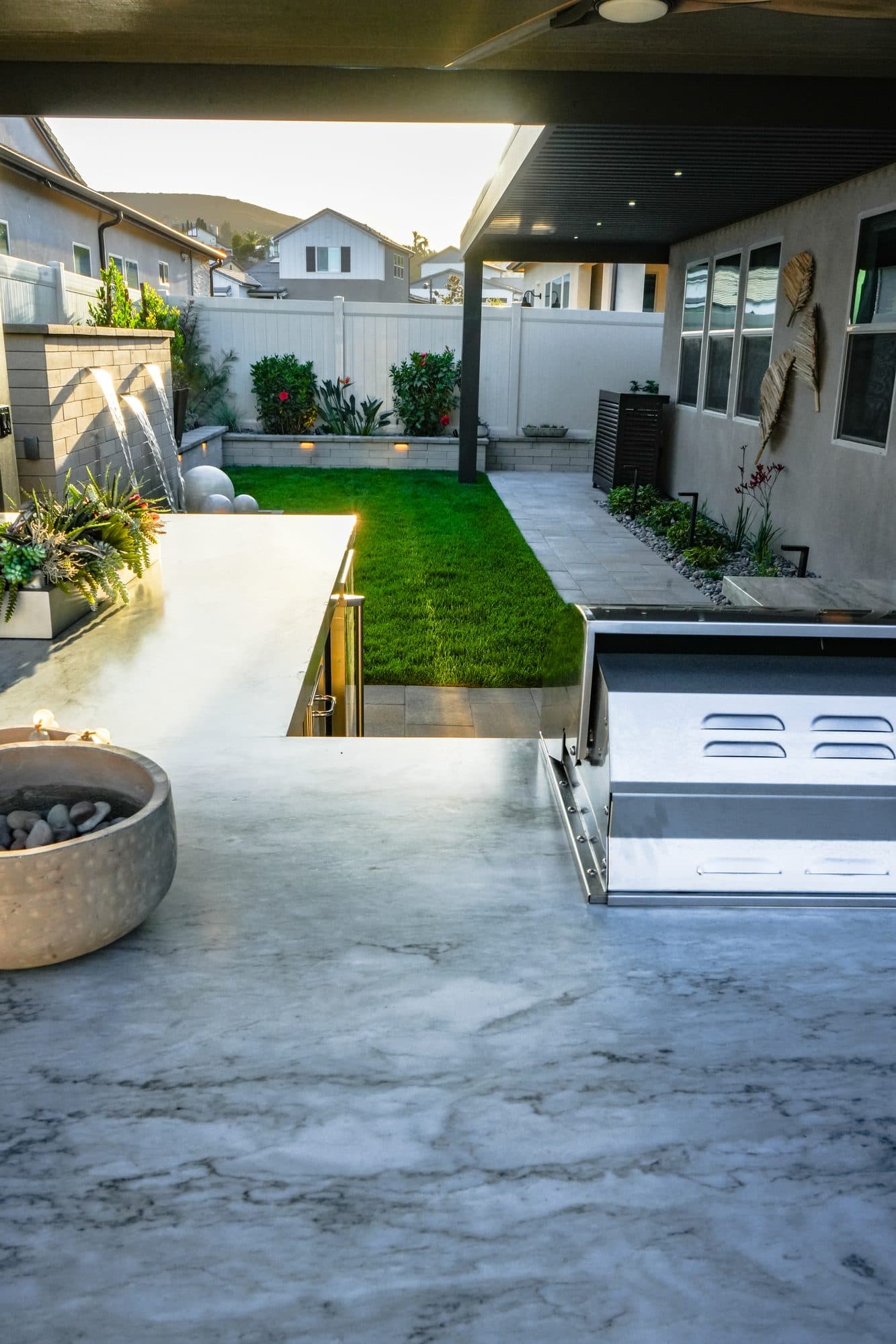 Outdoor kitchen and fire feature framed by the dual patio covers
