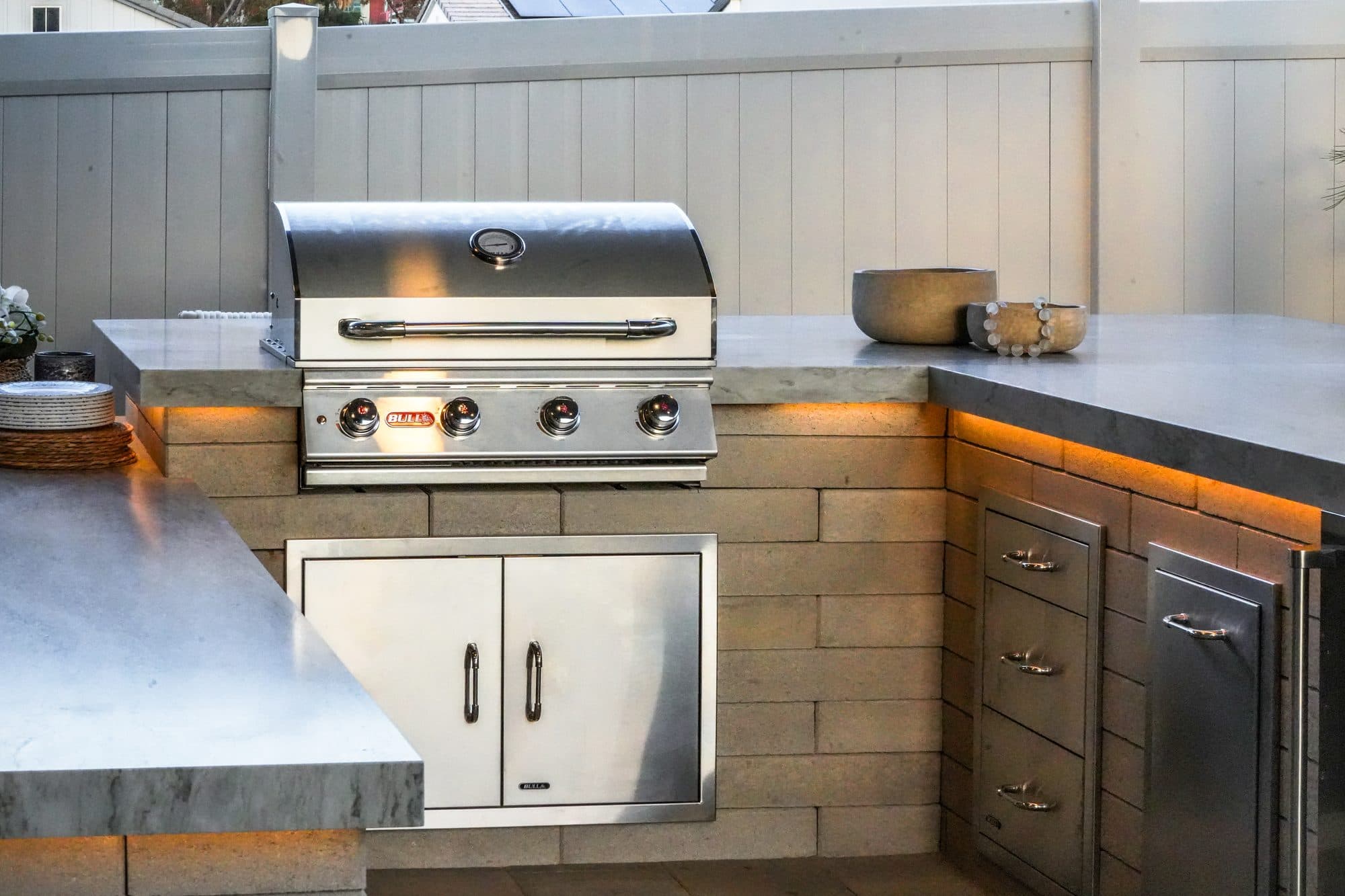 Built-in grill and stainless drawers in a stone outdoor kitchen by Modern Yardz in Rancho Bernardo