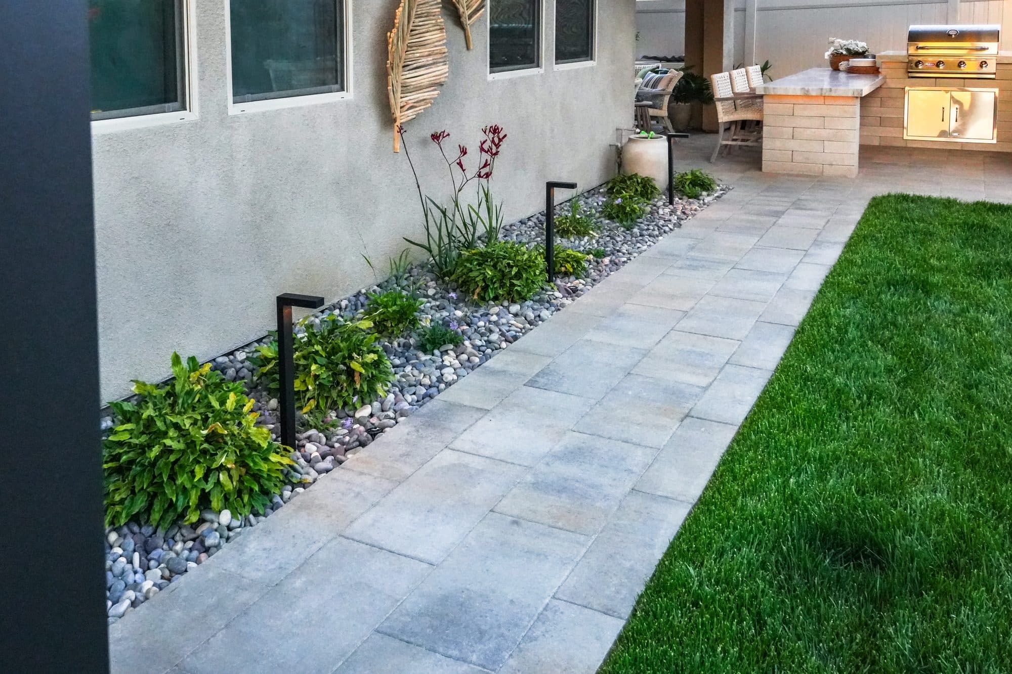 Paver walkway past the water feature and sod lawn toward the kitchen