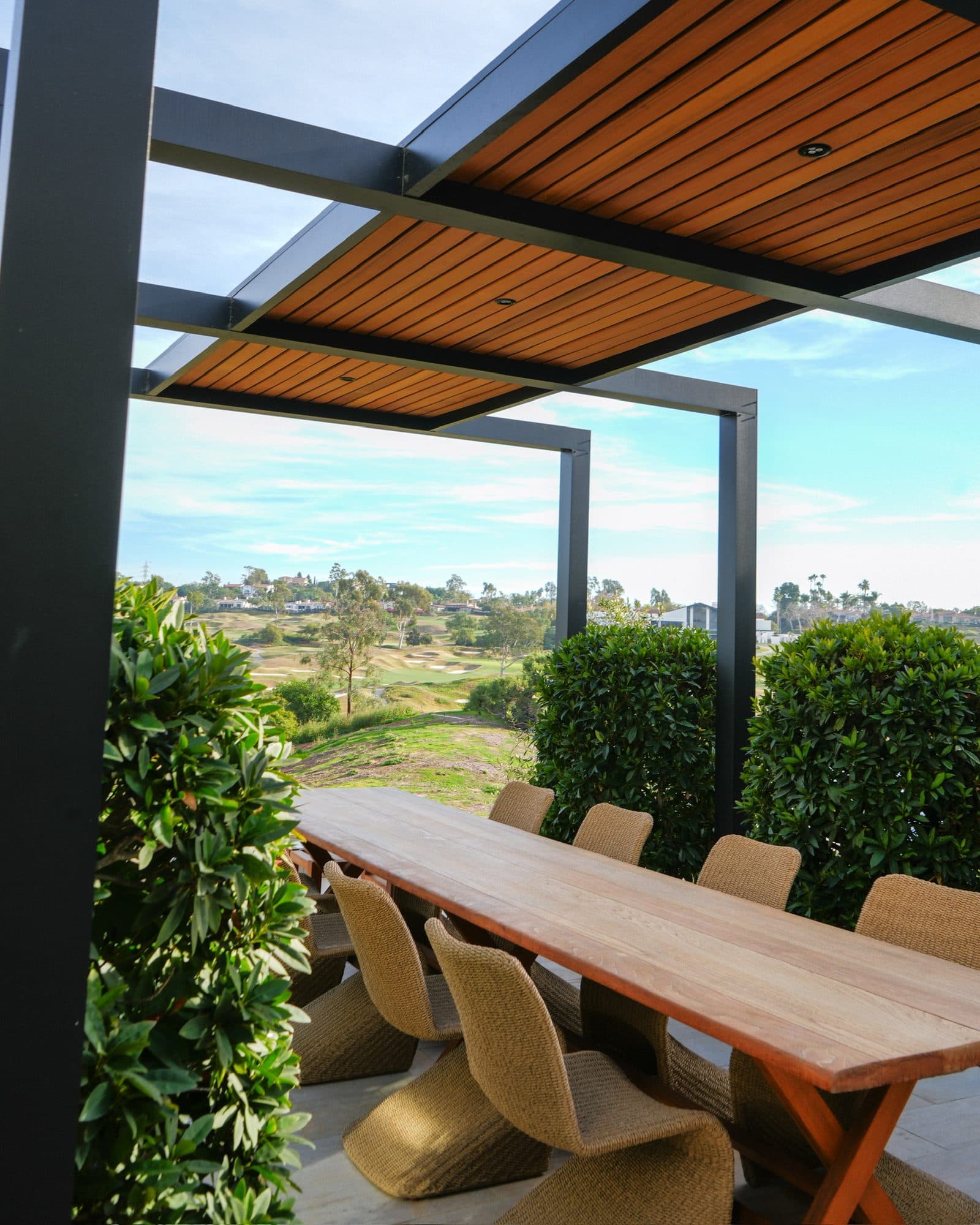 Long outdoor dining table under steel arbor beams by Modern Yardz in Rancho Santa Fe