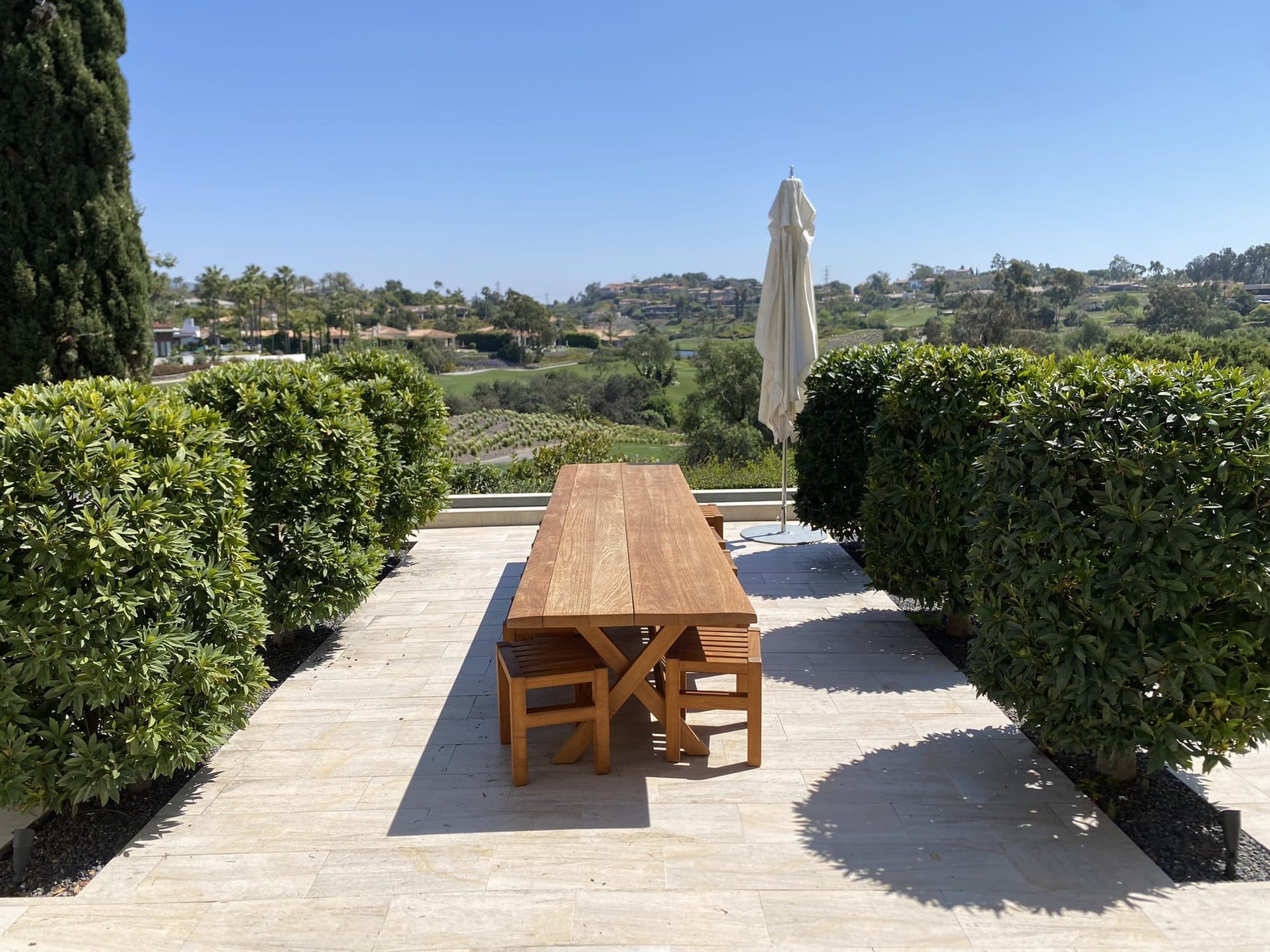 Dining table under the steel arches flanked by clipped hedges
