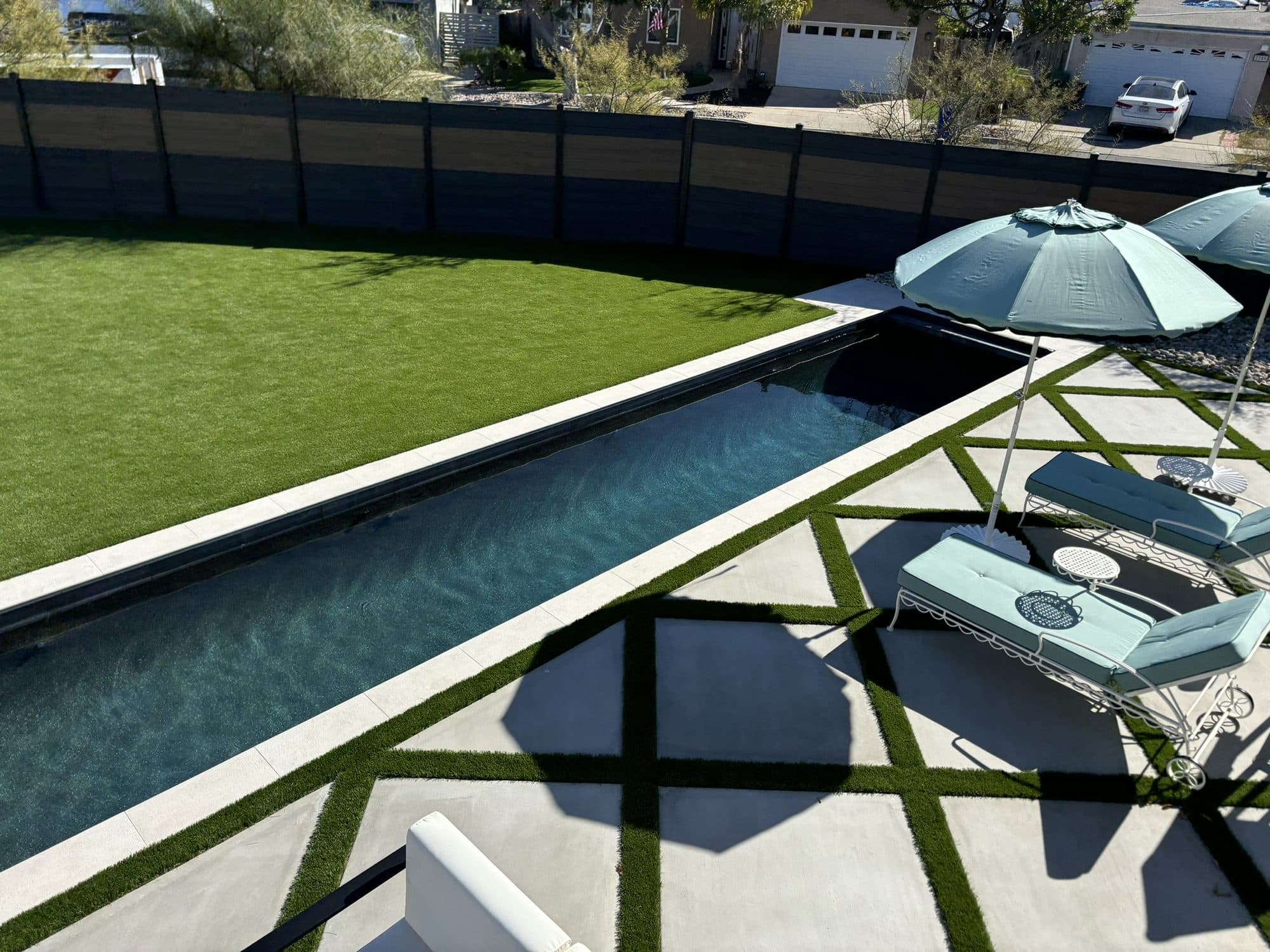 Aerial view of the completed backyard with a lap pool, diamond-patterned concrete and turf inlays in San Diego