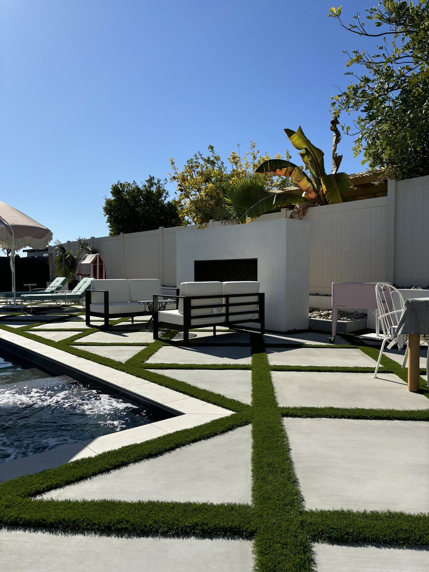 Diamond-patterned pour-in-place concrete with artificial turf inlays beside the pool