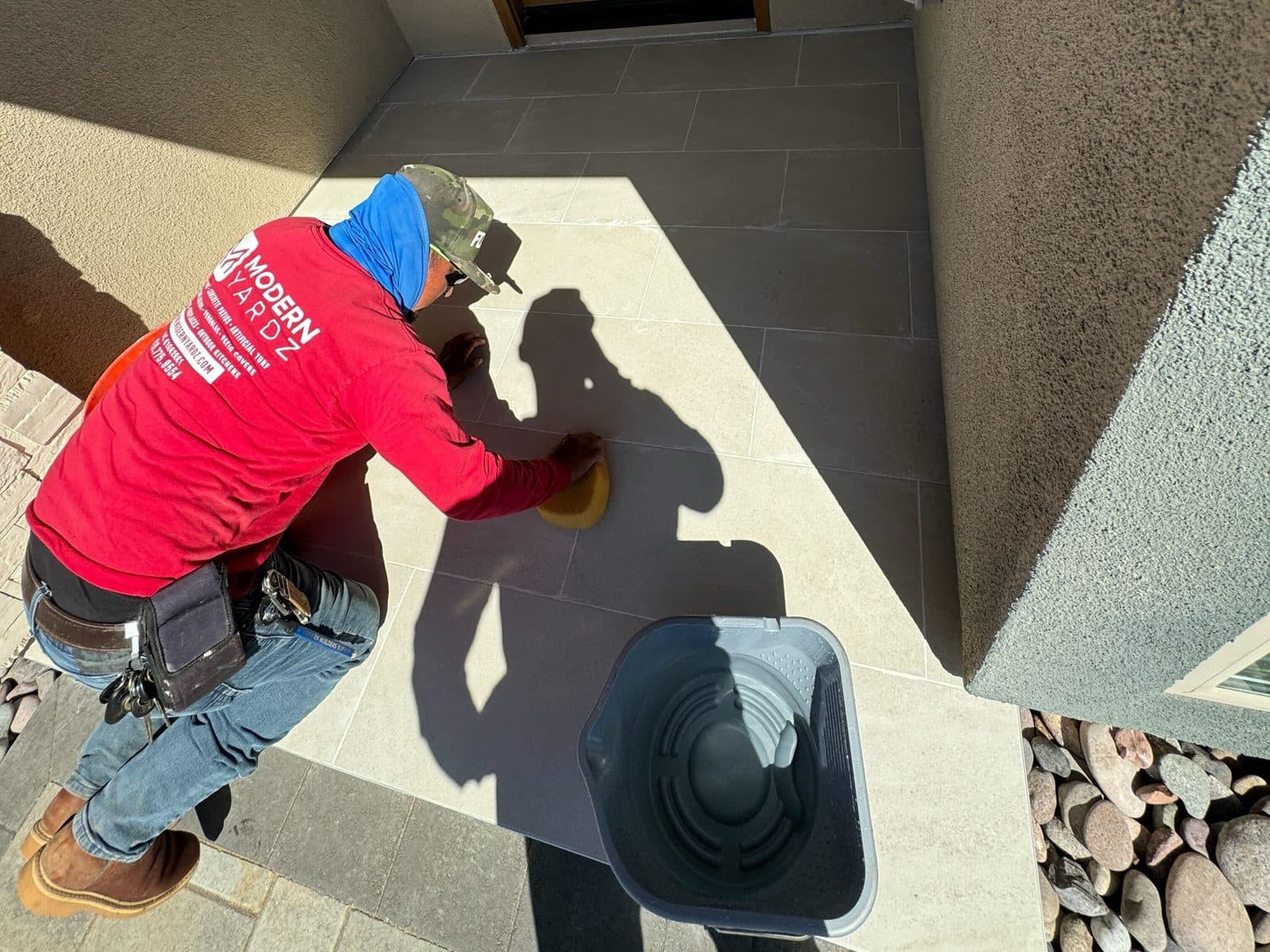 Modern Yardz installer polishing a porcelain paver entry landing in San Diego