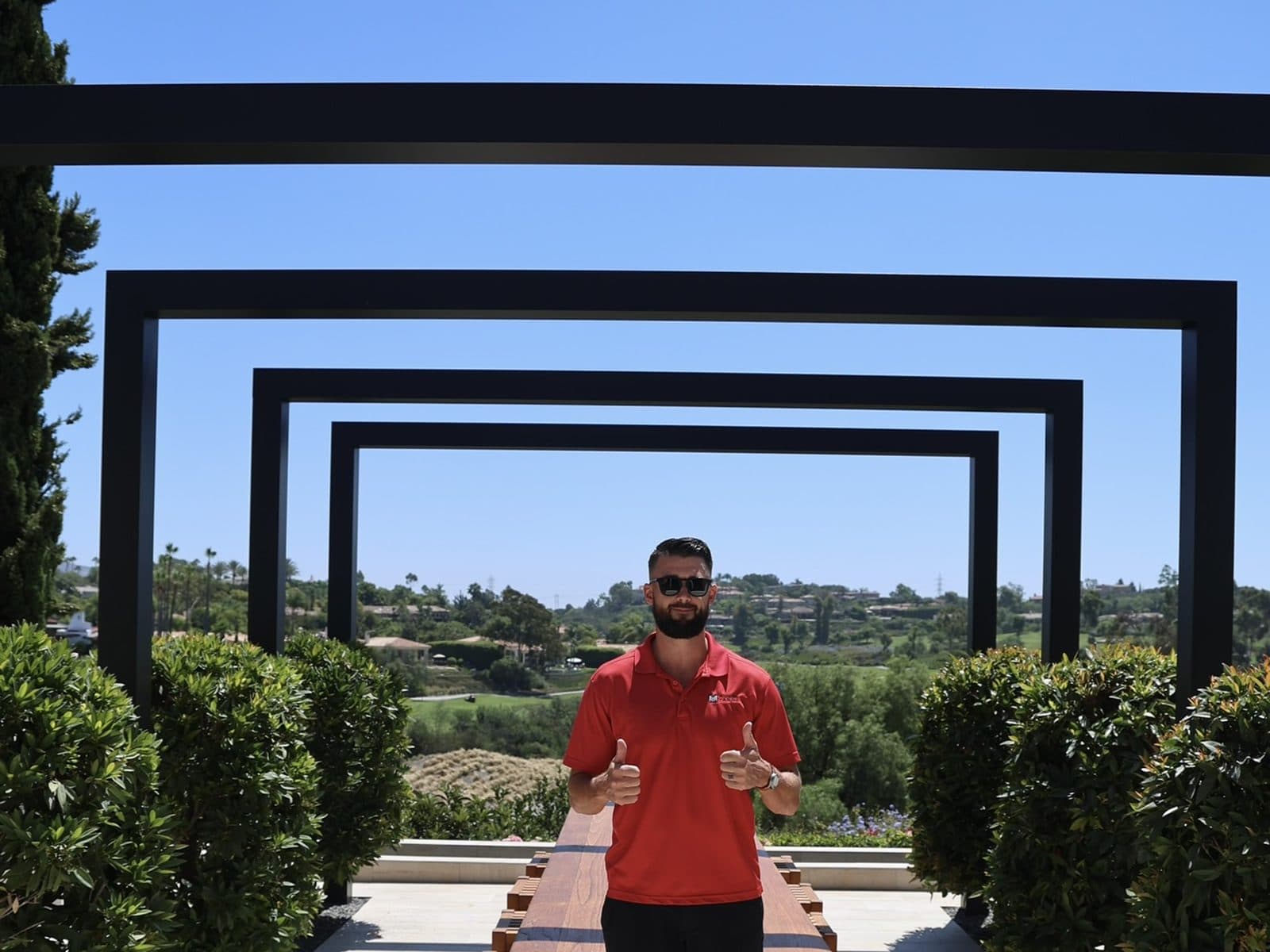 Black steel pergola framing an outdoor dining table with golf course views, built by Modern Yardz in San Diego